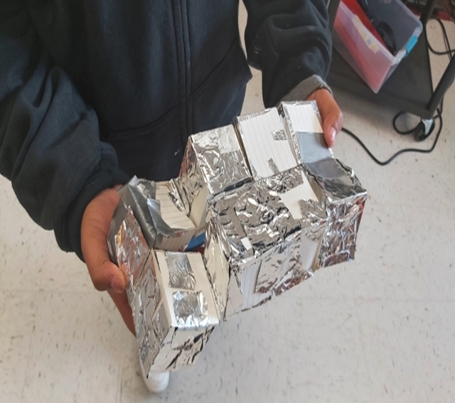 Student demonstrating a paper-based flexi-cube three dimensional model.